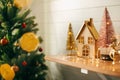 Merry Christmas. Stylish christmas wooden house, glitter christmas tree and golden reindeer in festive lights. Miniature fairy Royalty Free Stock Photo