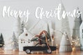 Merry Christmas text on festive Christmas scene, miniature holiday village. Car with christmas tree, little houses and snowy trees Royalty Free Stock Photo