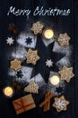 Merry Christmas text greeting card with gingerbread cookies, spices and candles on a star from icing sugar on dark blue wooden Royalty Free Stock Photo