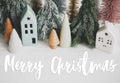 Merry Christmas text handwritten on christmas little houses and trees on white background,  winter holiday village scene. Greeting Royalty Free Stock Photo