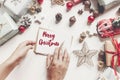 merry christmas text, seasonal greetings card sign. hands holding pencil and writing a letter wish list or greeting flat lay wit Royalty Free Stock Photo
