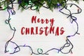 Merry christmas text sign on frame of garland lights on fir bra Royalty Free Stock Photo