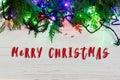 Merry christmas text sign on frame of garland lights on fir bran Royalty Free Stock Photo