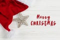Merry christmas text sign on golden star and santa hat on white Royalty Free Stock Photo