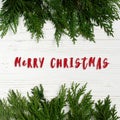 merry christmas text sign on green tree branches frame on stylish white rustic wooden background. space for christmas text. Royalty Free Stock Photo