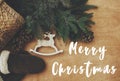Merry Christmas text sign on reindeer toy, gloves, basket with fir branches and cones on rustic wooden background. Flat lay. Zero Royalty Free Stock Photo