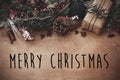 Merry Christmas text sign on stylish rustic christmas gift box with wreath, fir branches, berries, anise, pine cones, cinnamon on Royalty Free Stock Photo