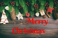 Merry Christmas text. Top view of frame made of fir tree branches and holiday decorations on wooden background Royalty Free Stock Photo