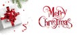 Merry Christmas text on white background with gift boxes, ribbons, red decoration, fir branches, bokeh, sparkles and confetti. Royalty Free Stock Photo