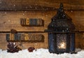 Merry Christmas text on a wooden background with burning lantern