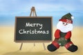 Merry Christmas word on blackboard and Santa Claus on tropical beach background Royalty Free Stock Photo