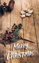 Merry Christmas word with mistletoe leaf and pine cone on wood plank table with sunlight through window..festive winter holiday