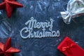 Merry Christmas words and gift boxes with red stars on grey background. Royalty Free Stock Photo