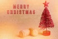 Merry Christmas written by sparkly red brush. Red artificial Christmas tree with champagne cork on bright background Royalty Free Stock Photo