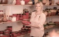 Merry female customer picking red glazed crockery Royalty Free Stock Photo