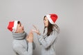 Merry fun couple girl guy in red Santa Christmas hat gray sweaters scarves isolated on grey wall background, studio Royalty Free Stock Photo