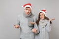 Merry fun couple girl guy in red Santa Christmas hat gray sweaters scarves isolated on grey wall background, studio Royalty Free Stock Photo