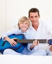 Merry little boy playing guitar with his father Royalty Free Stock Photo