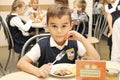 Merry schoolboy Sitting At Table In School Cafeteria Eating Meal. drinking juice - Russia, Moscow, the first High School, the firs Royalty Free Stock Photo