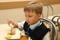 Merry schoolboy Sitting At Table In School Cafeteria Eating Meal. drinking juice - Russia, Moscow, the first High School, the firs Royalty Free Stock Photo