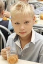 Merry schoolboy Sitting At Table In School Cafeteria Eating Meal. drinking juice - Russia, Moscow, the first High School, the firs Royalty Free Stock Photo