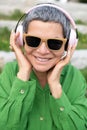 Merry senior woman listening to music in park
