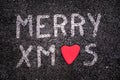 Merry xmas written on asphalt road, red stone in the shape of a heart Royalty Free Stock Photo