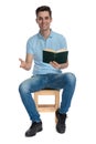 Merry young man laughing and holding a book