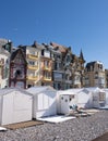 Beach cabins with people and colorful houses of mers les bains in french normandy