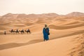 Merzouga, Morocco - APRIL 29 2019: MaroccanMoroccan standing in the sand in the Sahara Desert looking at the horizon