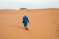 Merzouga, Morocco - APRIL 29 2019: Moroccan walking towards the camels