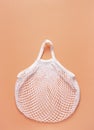 Mesh bag rests on a peach surface