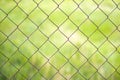 Mesh cage in the garden with green grass as background. Metal fence with wire mesh. Blurred view of the countryside through a Royalty Free Stock Photo