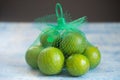 Mesh green plastic bag with a group fresh green lemons Royalty Free Stock Photo
