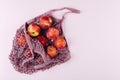 Mesh shopping bag with fruits plims and peach on pink background. Top view, flat lay Royalty Free Stock Photo