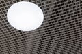 Mesh suspended ceiling with fluorescent or LED round lights in a modern shopping center or office building Royalty Free Stock Photo