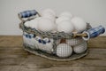 mesh vintage metal basket with fresh white chicken eggs on wooden table, valuable food product, Easter culinary traditions, close- Royalty Free Stock Photo