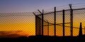 Mesh wire fence and barbeb wire at sunset Royalty Free Stock Photo