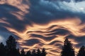 Mesmerizing cloud patterns illuminate the sky during sunset over a tranquil forest landscape Royalty Free Stock Photo