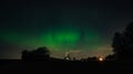 aurora bored lights shining in the dark night sky in a rural landscape with trees