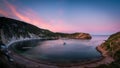 Mesmerizing seascape displaying a sailing boat floating on the Lulworth Cove bay during sunset