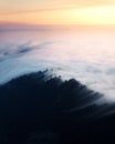 Mesmerizing shot of clouds covering the peaks of tree-covered mountains