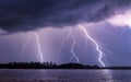 Mesmerizing shot of multiple lightning strikes by a river with a dark blue sky Royalty Free Stock Photo
