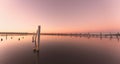 Mesmerizing sunset over a calm sea, with pier poles and people walking on the jetty walk Royalty Free Stock Photo