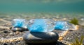 Blue watery capsules rest on stones underwater Royalty Free Stock Photo