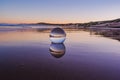 Mesmerizing view of a clear crystal ball placed on the sand near the beach during the sunset Royalty Free Stock Photo