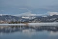 Mesmerizing view of lake water reflecting the snow-covered hill with leafless trees Royalty Free Stock Photo