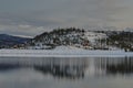 Mesmerizing view of lake water reflecting the snow-covered hill with leafless trees Royalty Free Stock Photo