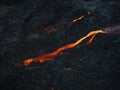 Red hot lava flow streaming over black volcanic rocks, aerial directly above Royalty Free Stock Photo