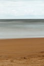 Mesmerizing view of the ocean hitting the sandy beach under the cloudy blue sky Royalty Free Stock Photo